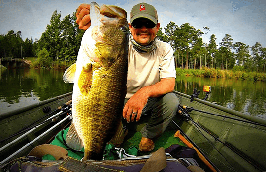 A Man Holding a Giant Bass Fish on a Boat