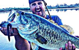 Man holding large bass on a hook and a fishing rod