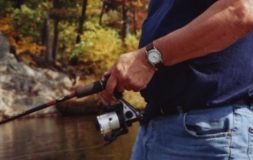 Man in a blue shirt holding fishing rod in the fall