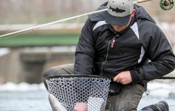 Man in the black jacket holding fishing rod and a fishing net