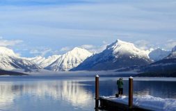 Man preparing to fish in the lake with snowy mountains behind