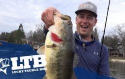 Man smiling holding a big fish and fishing rod with ltb logo