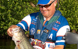 Man with a blue hat holding fish smiling