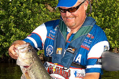 Man with a blue hat holding fish smiling