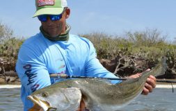 Man with a green hat holding large trophy trout