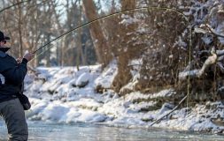 Man with a hat fishing flying rod in the winter