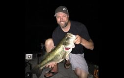 Man with a hat holding large fish at night