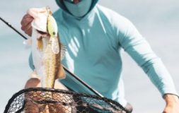 Man with a hat pulling bass out of the shallow water