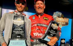 Two men hugging holding trophies