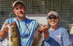 Woman standing next to a man holding two fish