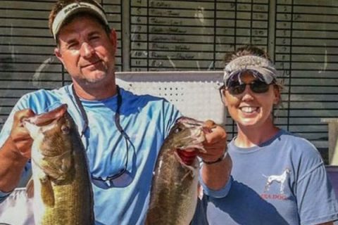 Woman standing next to a man holding two fish